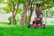 Photo of CRAFTSMAN red lawn mower CM12ABO2C2093 in use on grass under trees, front angle.