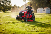 Photo of Craftsman riding lawn mower CM14AHA6ZMA93 cutting grass on a sunny lawn, home and shed in background.
