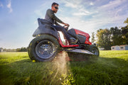 Photo of Craftsman riding lawn mower, SKU CM14AHA6ZMA93, side view on grass, with rider mowing in daylight.