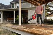 Person using Craftsman leaf blower, SKU CMCBL730P1, in a wooded yard clearing leaves, product held at side.