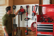 Photo of CRAFTSMAN chainsaw CMCCS620M1 hung on garage wall with red tools and tool chest.