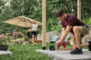 Photo of Craftsman drill CMCD716 used outdoors for construction, man drilling into concrete near wooden posts.