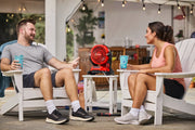 Photo of Craftsman portable red fan CMCE003B on patio table between two people seated in white chairs.
