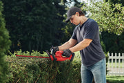 Photo of CRAFTSMAN CMCHT810C1 cordless hedge trimmer in use outdoors on shrubbery.