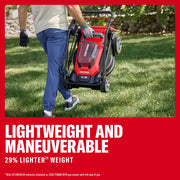 Photo of a person carrying a folded Craftsman cordless lawn mower CMCMWP120M2 by the handle over grass.