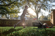 Photo of a person pushing a Craftsman walk-behind lawn mower, SKU CMCMWSP320X2, mowing grass in a backyard.