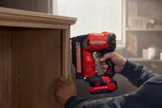 Photo of Craftsman cordless nailer CMCN623B in use attaching trim to wooden cabinet, side angle.