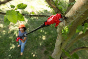 Photo of a CRAFTSMAN pole pruner, SKU CMCPPR320B, being used to trim a tree branch outdoors by a person wearing safety gear.