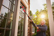 Photo of Craftsman CMCPS520B power scrubber cleaning tall outdoor windows, held by user in daylight.