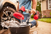 Photo of Craftsman CMCPS520B power scrubber with red brush cleaning in water, outdoor setting.