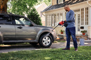Photo of person washing SUV with Craftsman CMCPW350D1 cordless power cleaner in driveway, house in background.