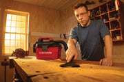 Photo of Craftsman wet/dry vacuum CMCV002B on workbench in a woodshop with a person cleaning sawdust.