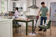 Photo of Craftsman CMCVS501M1 cordless stick vacuum cleaning kitchen floor near green chairs.