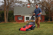 Photo of CRAFTSMAN lawn mower CMEMW213 in use on grass by a person, with a red brick house in the background.