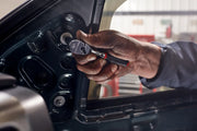 Photo of a hand using a CRAFTSMAN ratchet, SKU CMMT86304V, to tighten a bolt inside a car door panel.