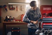 Photo of a person working on a motorcycle in a garage with CRAFTSMAN tool storage, SKU CMMT87021 visible in background.