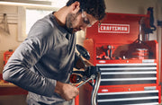 Photo of a person using a wrench on a motorcycle handlebar with CRAFTSMAN tool chest CMMT87022 in the background.