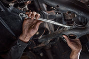 Photo of mechanic using CRAFTSMAN wrench SKU CMMT87400V on car suspension component in a workshop setting.
