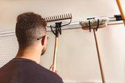 Photo of person placing rake on CRAFTSMAN wall storage rail, SKU CMST22000, for organizing long-handle tools.