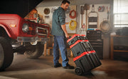 Photo of CRAFTSMAN rolling tool box stack CMST60403, black and red, in a garage, pulled by a person.