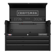 A black Craftsman-branded tool chest with an open top lid and three drawers. The interior back panel features pegboard holes, an integrated power strip, and silver text that reads '1776 USA 2026'. The product also has USA and Craftsman logos on the front.
