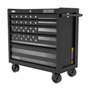 A black rolling tool chest with multiple drawers, featuring an American flag design on the front. The chest has caster wheels for mobility and a handle on the side. The brand name 'Craftsman' is displayed at the top.