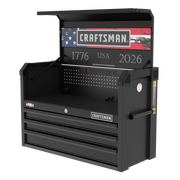 A black Craftsman tool chest with three drawers, an open top compartment, and a built-in pegboard. The chest features an American flag design, the years '1776' and '2026', and 'USA' displayed inside the lid. The tool chest also includes a set of electrical outlets built into the back panel.