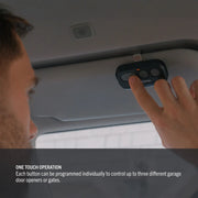 Photo of a person pressing a CRAFTSMAN CMX363 garage door opener remote mounted on a car sun visor.