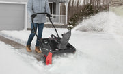 Person clearing snow on driveway with Craftsman snow blower CMXGBAM1054539, black and red, outdoor use.