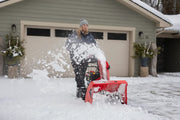 Photo of CRAFTSMAN snow blower SKU CMXGBAM213102 clearing snow in front of a house.