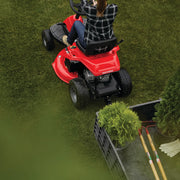 Photo of a person riding a red Craftsman riding lawn mower CMXGRAM1130035 near a garden cart with plants and garden tools.