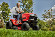 Photo of Craftsman riding lawn mower CMXGRAM201302 outdoors, red body, black wheels, side view.