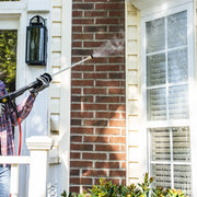 Photo of a CRAFTSMAN pressure washer CMXGWFN061294 spraying water on a house window and brick wall exterior.
