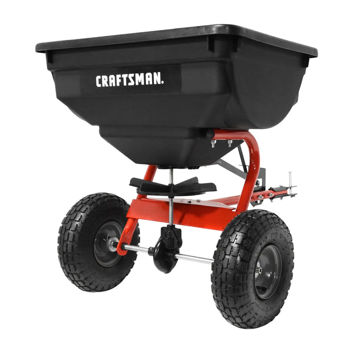 Photo of Craftsman tow-behind spreader CMXGZBF4505561 with black hopper and red frame on white background.