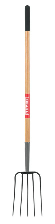 A garden pitchfork with a long wooden handle and four metal tines, featuring a black grip at the top and a red label on the handle.