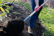 Photo of CRAFTSMAN shovel CMXMLTP35325 in use, moving soil in a garden with red CRAFTSMAN branding visible.