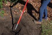Photo of CRAFTSMAN garden hoe SKU CMXMLTP35335 with red handle, shown in use on soil and leaves outdoors.