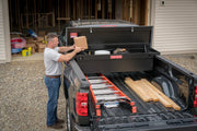 Photo of Craftsman CMXTBAK1055301 black truck tool box open in a pickup bed, with man loading tools and materials.