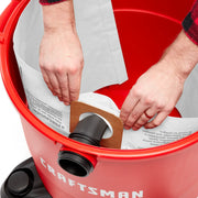 Photo of CRAFTSMAN CMXZVBE38749 vacuum with hands installing a filter bag inside red canister, front angle.