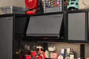 A Craftsman branded metal storage cabinet with a flap door is mounted on a wall above a workbench. Various tools and