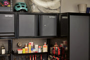 A close-up view of a workshop storage area featuring black CRAFTSMAN wall cabinets and a tall cabinet. The cabinets are